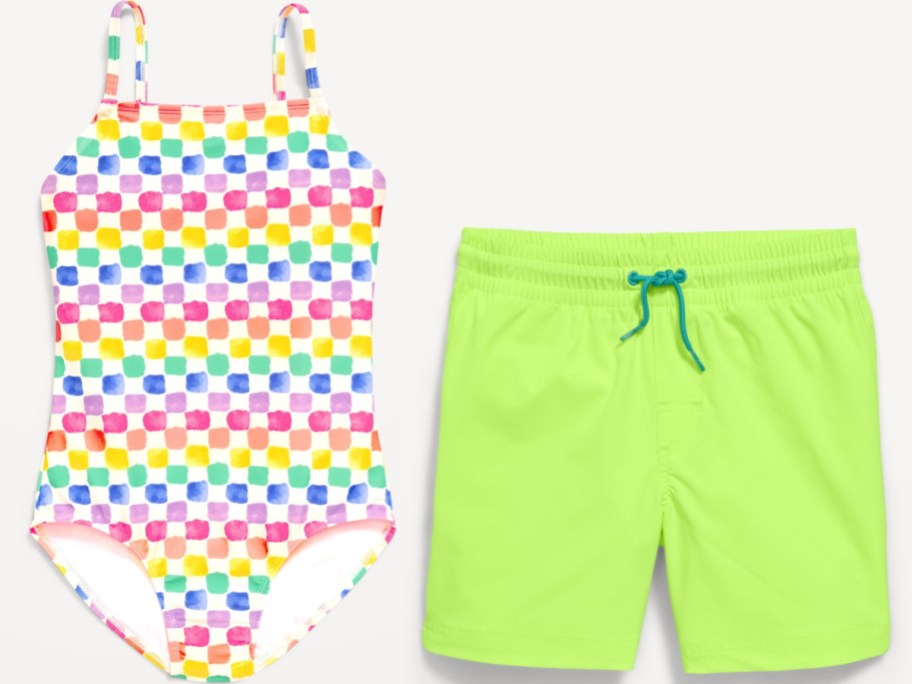 Bright swimsuit set: A colorful plaid one-piece swimsuit with a rainbow pattern sits next to neon green swim trunks with blue drawstrings.