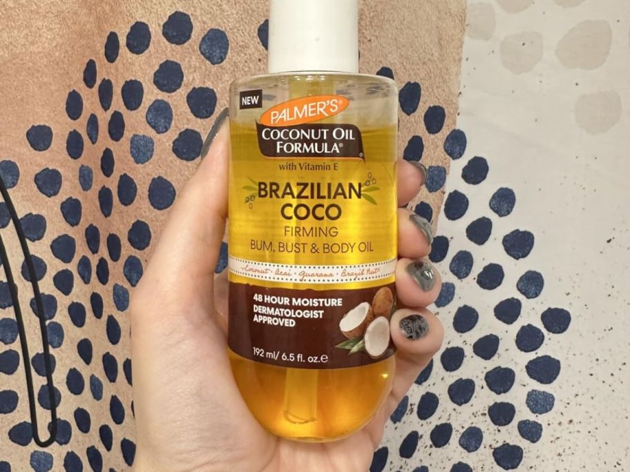 hand holding Palmer's Coconut Oil Formula Brazilian Coco Firming Body Oil