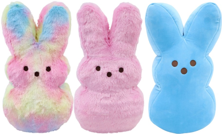 Three plush bunny toys are shown. The first is rainbow-colored, the second is pink, and the third is blue.
