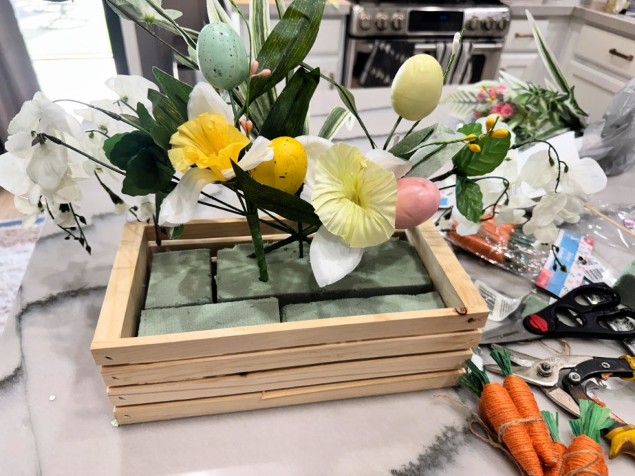 placing faux flowers inside an easter arrangement