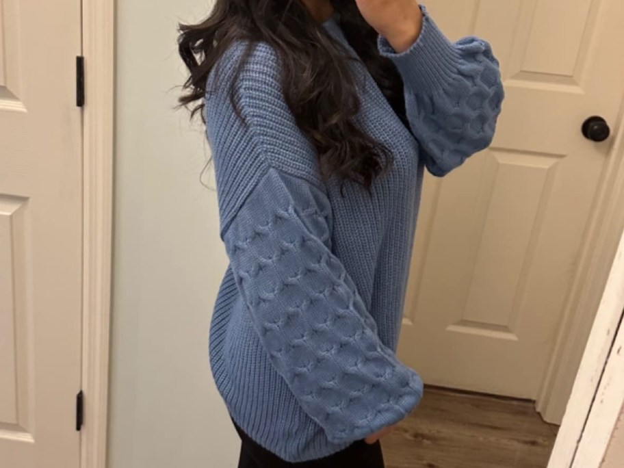 woman in blue sweater taking selfie from the side