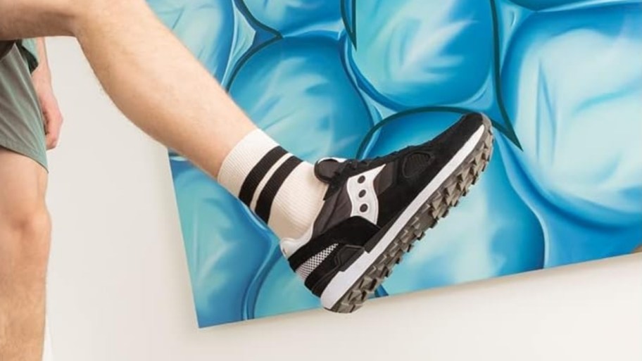 a mans foot wearing a black and white sneaker