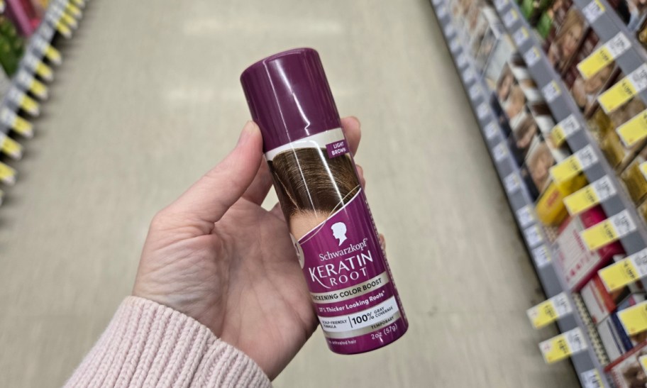 hand holding a can of hair root spray in a store aisle