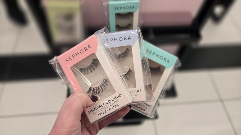 a hand holding three packs of false lashes