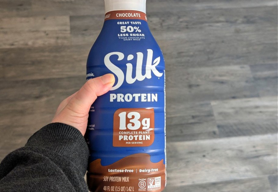 A hand holding up a bottle of chocolate silk protein milk.