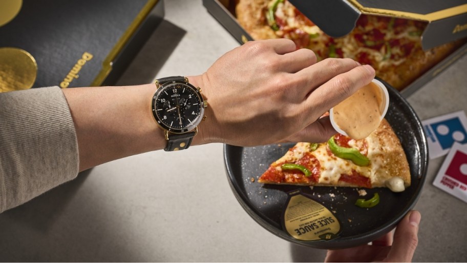 a hand pouring slice sauce over a pizza slice