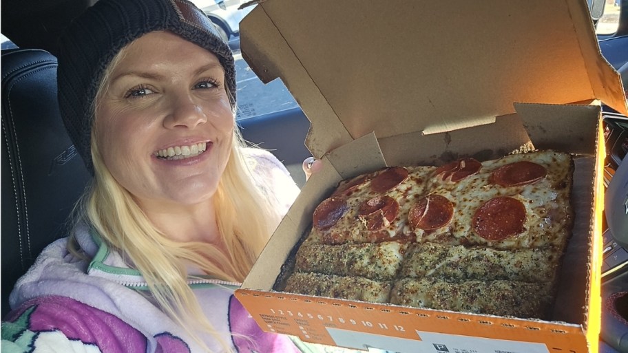a woman holding a box of Detroit-style Slices-n-Stix