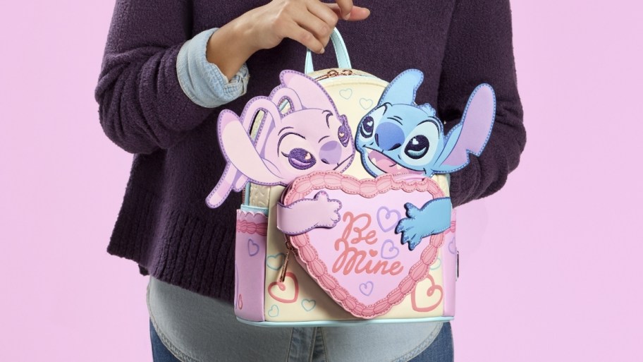 a woman holding an angel and stitch backpack