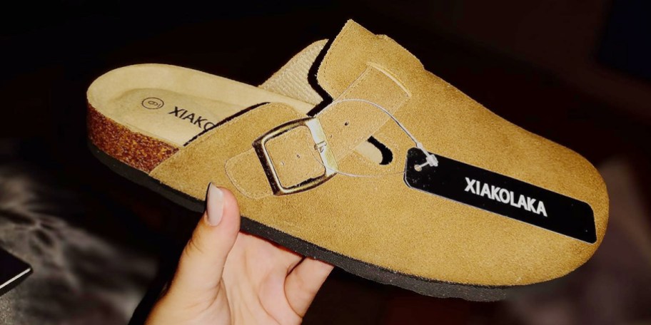 hand holding tan clogs