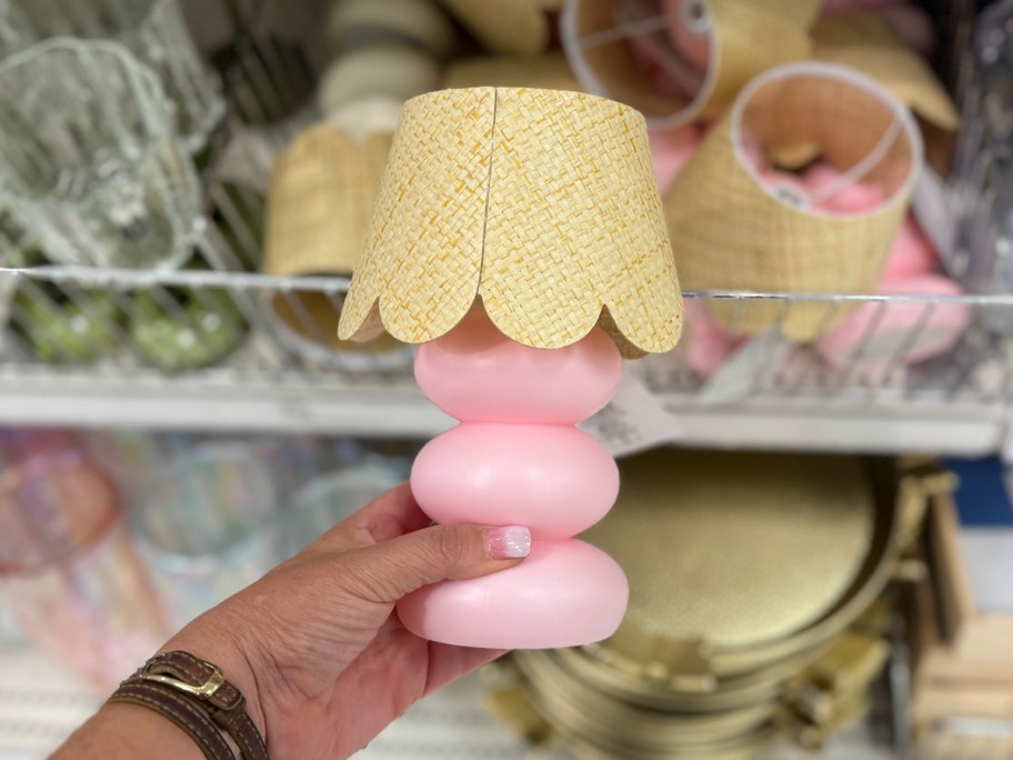 womans hand holding a small lamp with a woven shade