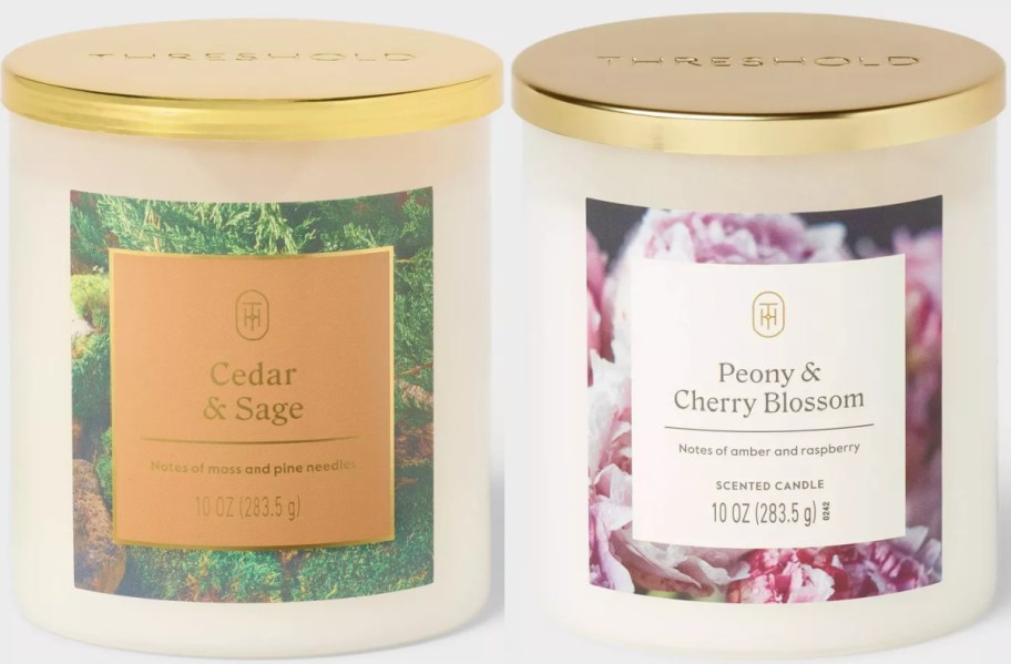 Two scented candles with gold lids. Left: Cedar & Sage, featuring moss imagery. Right: Peony & Cherry Blossom, with pink blossoms. Both are 10 oz.