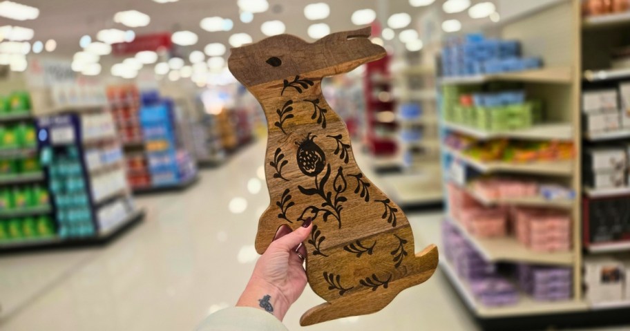 hand holding a wood bunny shaped serving board or decor piece in a store aisle
