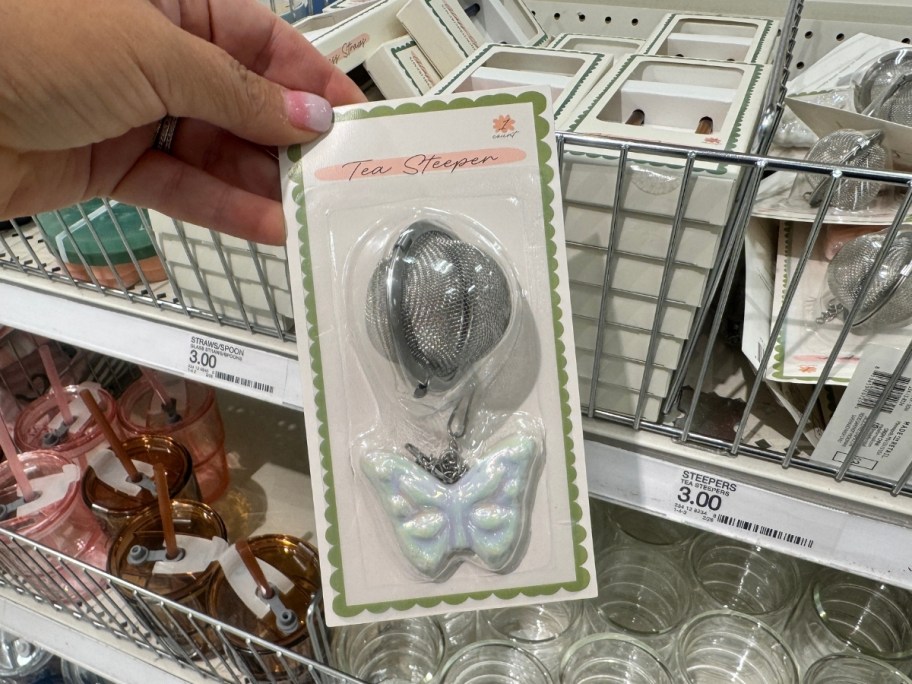 womans hand holding a tea steeper