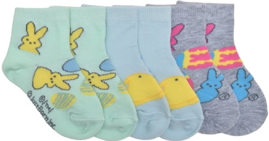 Four pairs of colorful socks featuring cute cartoon designs: yellow bunnies on green, yellow chicks on blue, and pink and blue bunnies on gray. 
