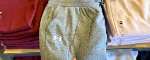 womnas hand grabbing a pair of sweatpants from a display table