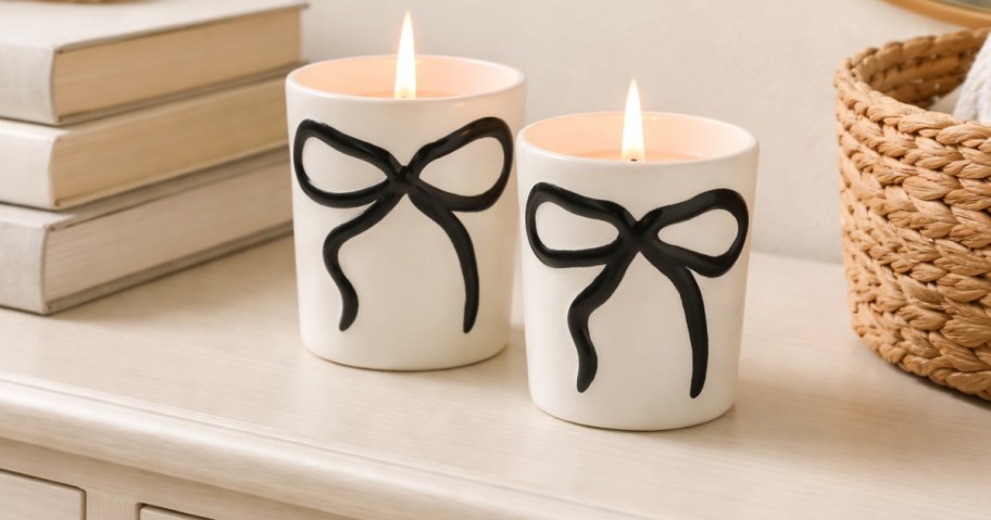 a set of candles with bows on them on a dresser