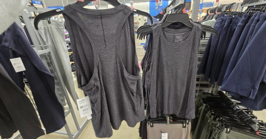 hand holding a racerback tank on a hanger next to more on a clothing rack