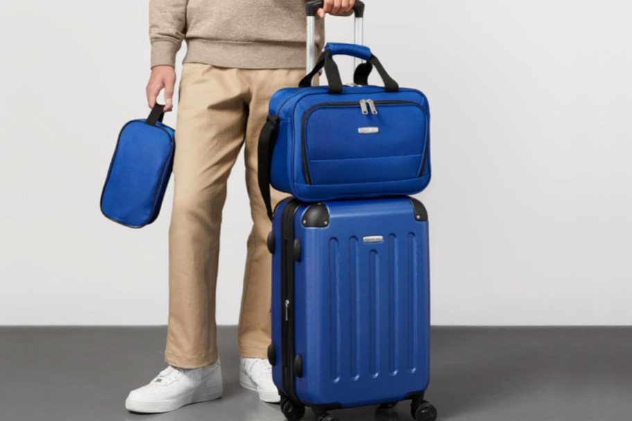 man standing behind two blue luggage with carry on stacked