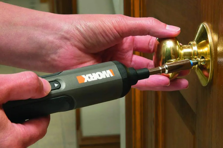 hand using electric screwdriver on doorknob