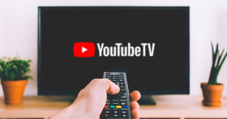 hand holding remote towards tv with youtube tv app on it
