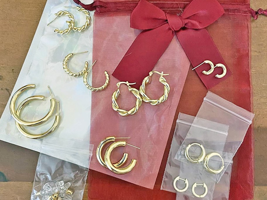 sets of gold hoop earrings on top of red gift bag