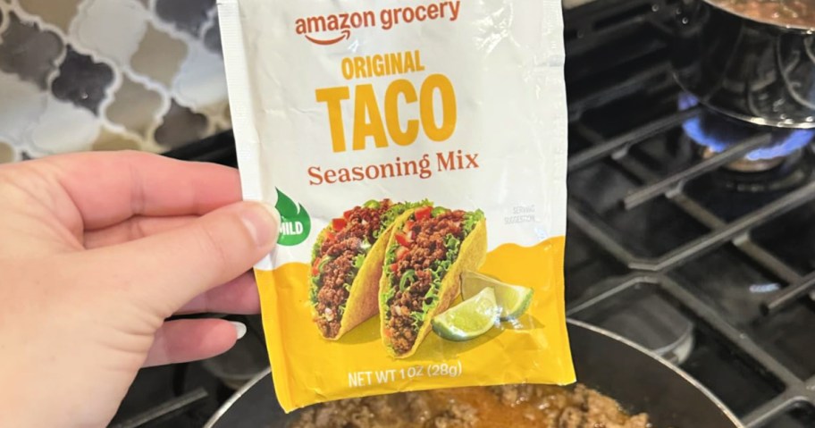 Hand holding up a packet of Amazon grocery original taco seasoning mix
