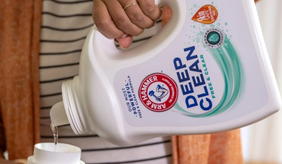 person pouring arm & hammer deep clean laundry detergent into cap for washing