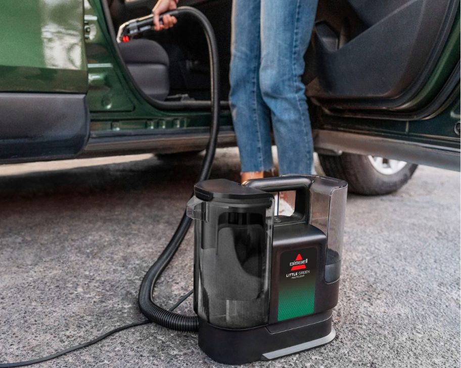 person using a BISSELL Little Green MultiClean Wet and Dry Portable Carpet and Upholstery Cleaner to clean out their car