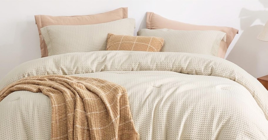 white comforter and shams set on a bed with a yellow throw blanket and pillow