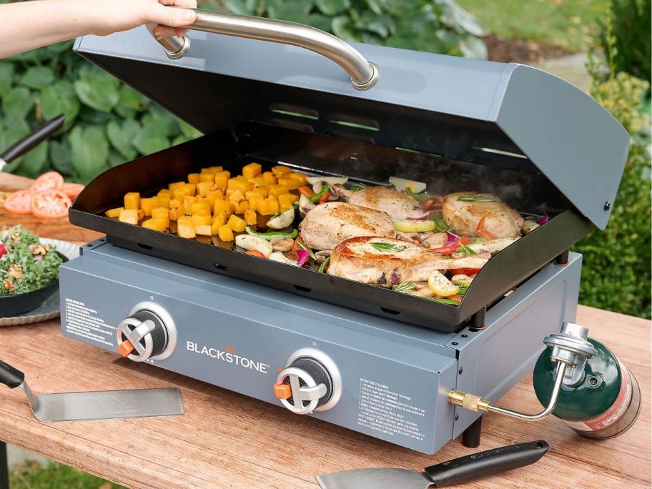 A Blue Blackstone Omnivore 22" Griddle with hood with chicken, potatoes and veggies cooking on it
