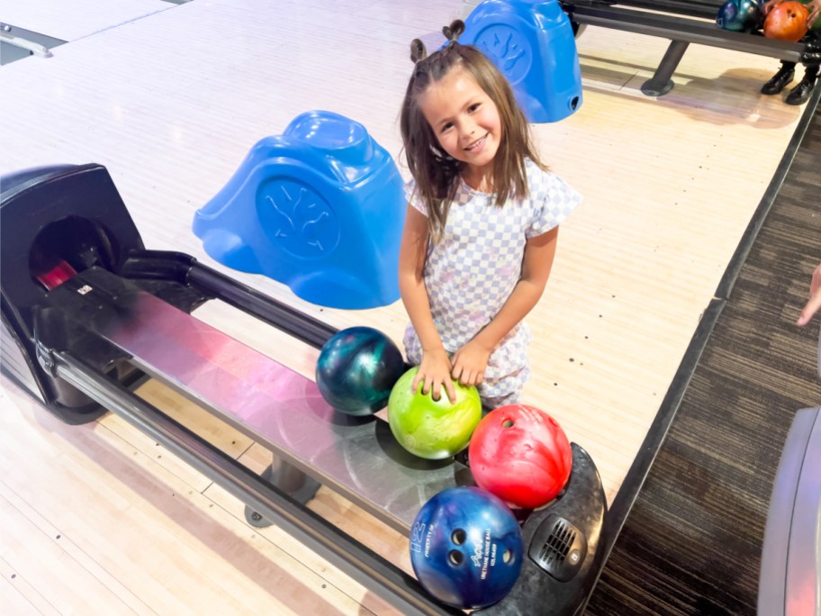 girl grabbing a bowling ball from return