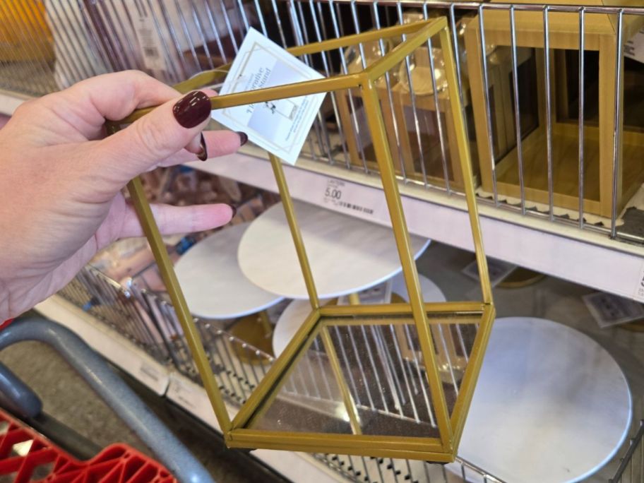 Hand holding a gold metal flower stand from Target's Bullseye's Playground