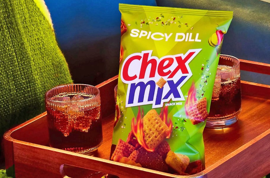 green bag of Chex Mix Spicy Dill near drinks on a wood tray