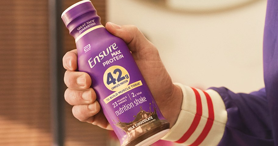 hand holding up a purple bottle of Ensure Max Protein Shake