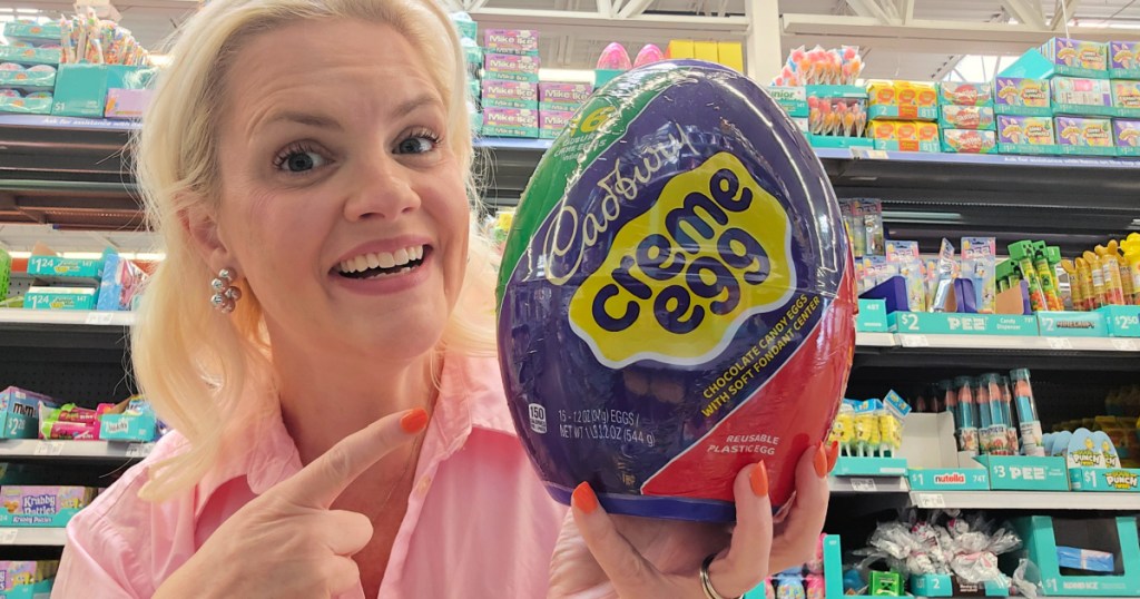 Woman wearing pink shirt, inside Walmart store and holding up giant Cadberry cream egg