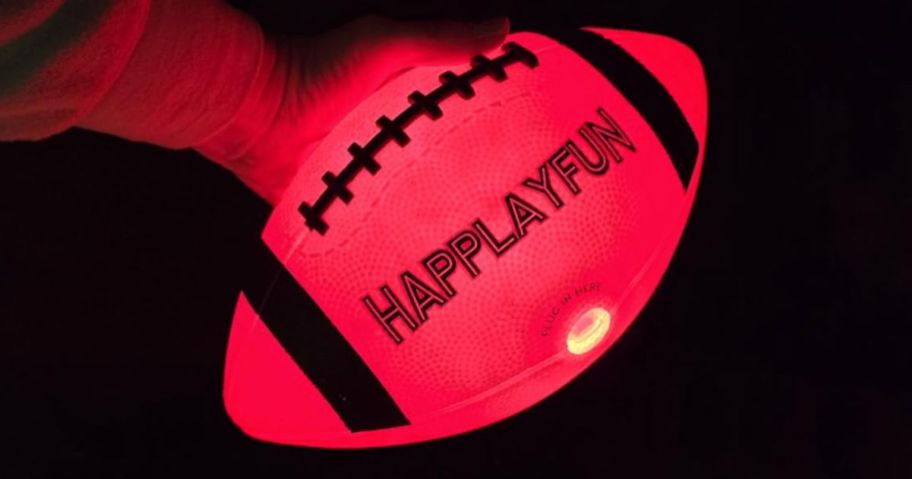 Hand holding a glowing hand in the dark soccer ball