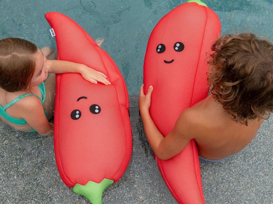 Two children using hot pepper float in pool