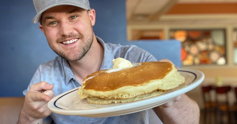 Man holding a plate of IHOP Pancakes