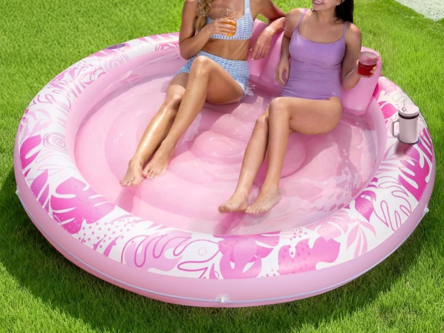 two women sitting in Inflatable 72" x 56" Tanning Pool in Pink