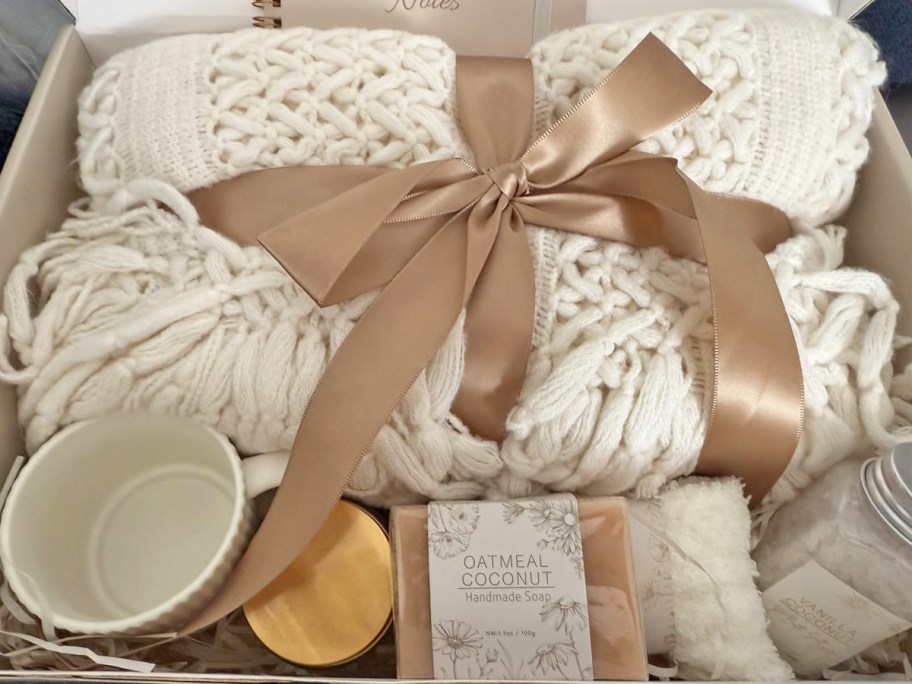 knitted blanket, candle, soap, and mug in a gift box