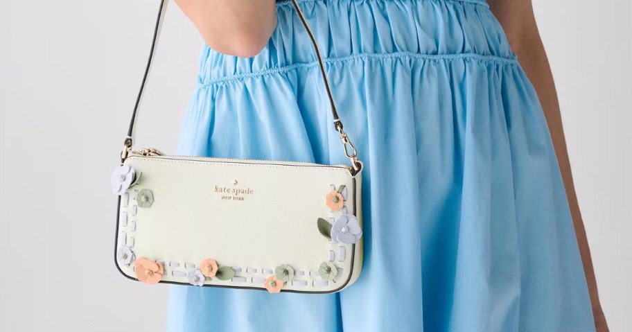 woman holding kate spade floral purse on arm wearing a blue dress