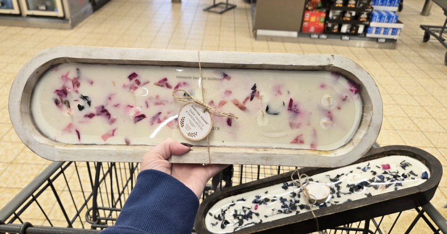hand holding up a large candle with another in background in a cart
