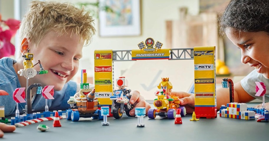 two boys playing with Mario Kart LEGO set on a table