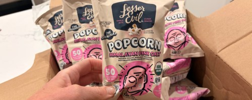 Woman holding up lesser evil popcorn, snack bags