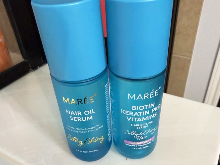 two blue bottles of MAREE hair oils