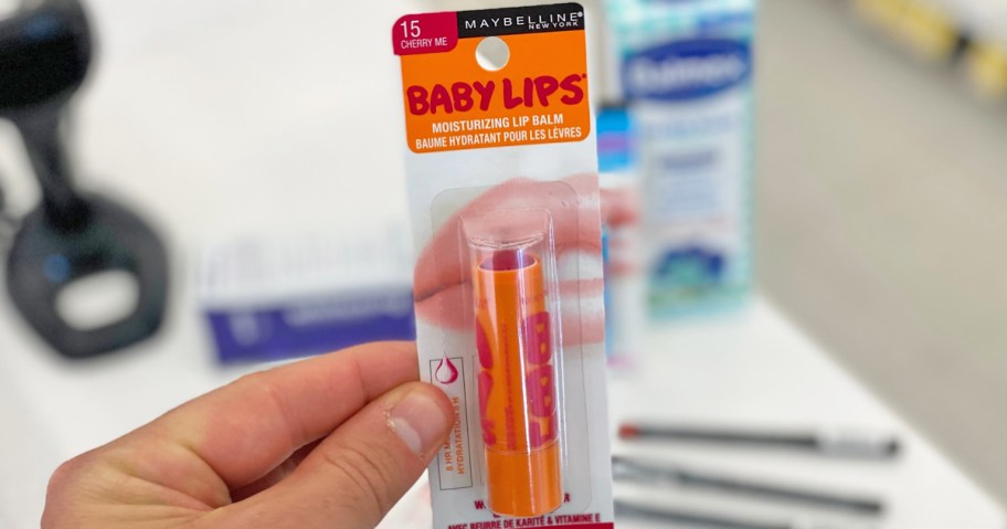 hand holding up and orange Maybelline Baby Lips lip balm in store