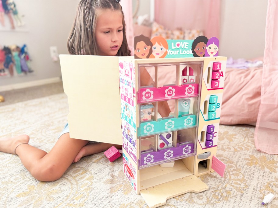 girl playing with a wooden beauty vending machine playset