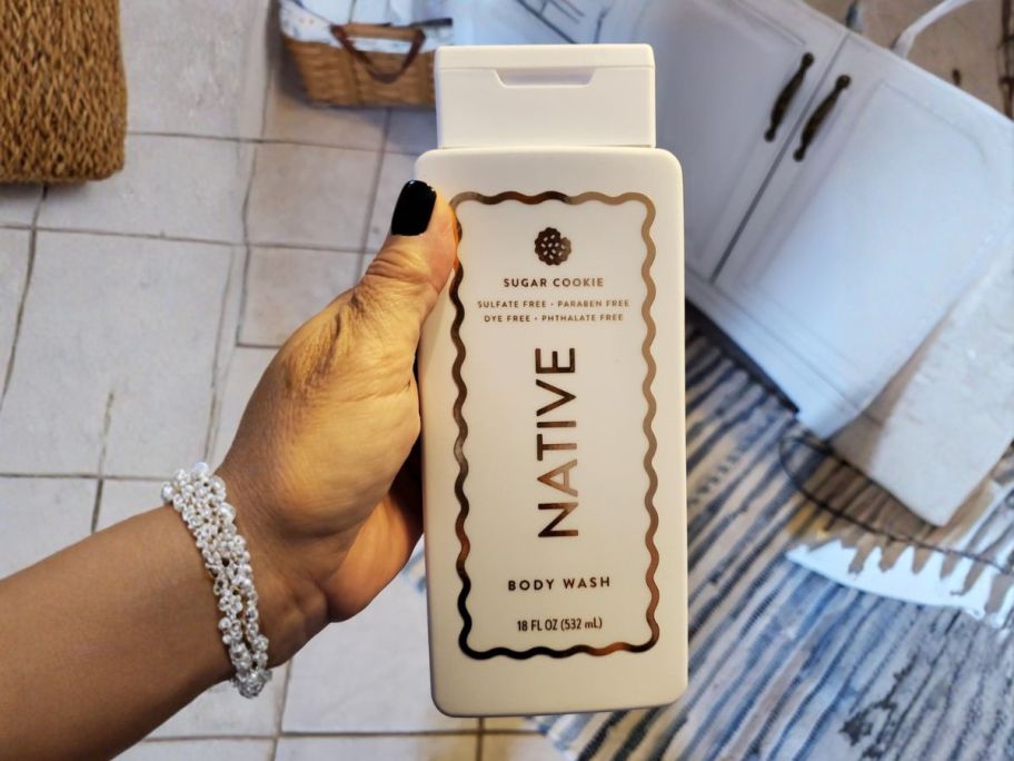 hand holding Native Sugar Cookie Scented 18oz Body Wash in bathroom
