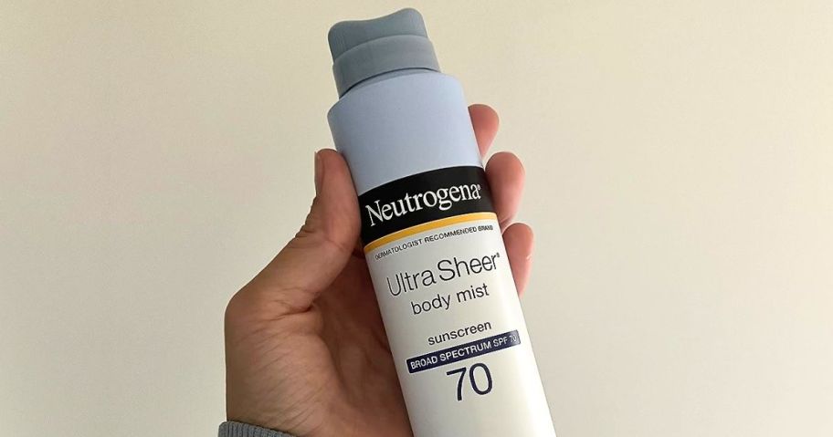 Hand holding a bottle of Neutrogena Sunscreen