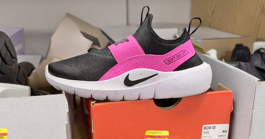black and pink nike sneaker on top of shoe box in store